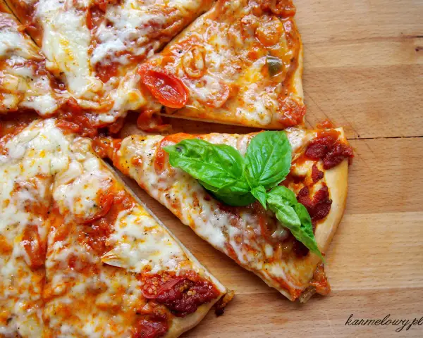 Szybki przepis na ciasto do pizzy: pyszna, domowa pizza z pomidorami i mozzarellą, ozdobiona świeżą bazylią.