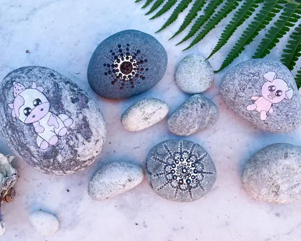 Söta djur och mandalas målade på stenar. En ko, en gris och två mönster.