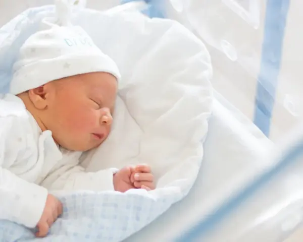 Śpiący noworodek w czepku z napisem "DADDY". To idealny moment na becikowe dla kogoś tak małego.