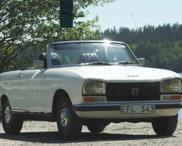Vit cabriolet Peugeot 304 står vid en sjö.