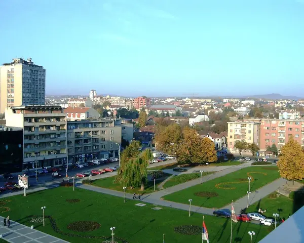Widok na centrum Kragujevac Serbia z budynkami mieszkalnymi, parkiem i ulicą pełną samochodów.
