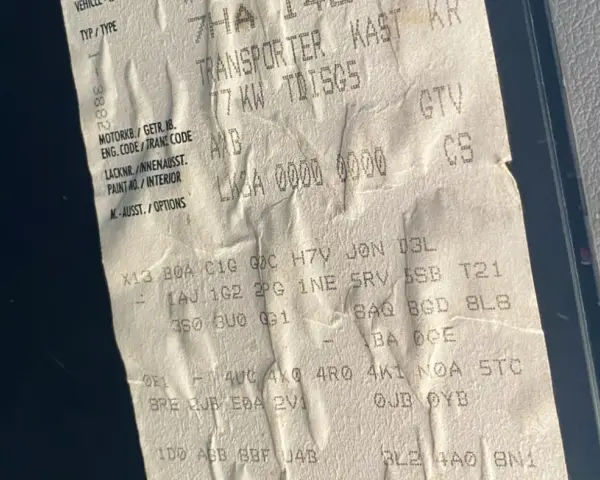 Aufkleber mit Fahrzeugdaten, um die PR-Nummern zu entschlüsseln. Zeigt Transporter, Motorcode AXB, Lacknummer und Optionen.