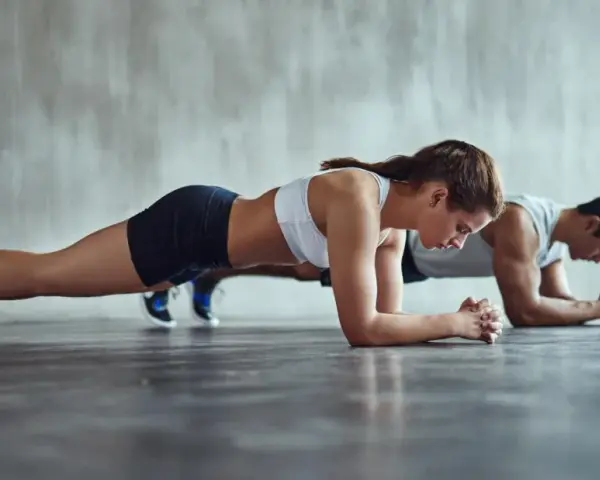 Un couple concentré fait la planche côte à côte dans une salle de sport.