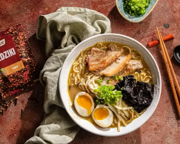 Jak zrobić ramen? Aromatyczny bulion, makaron, jajko na pół, plastry mięsa i nori. Obok paczka goździków Prymat.