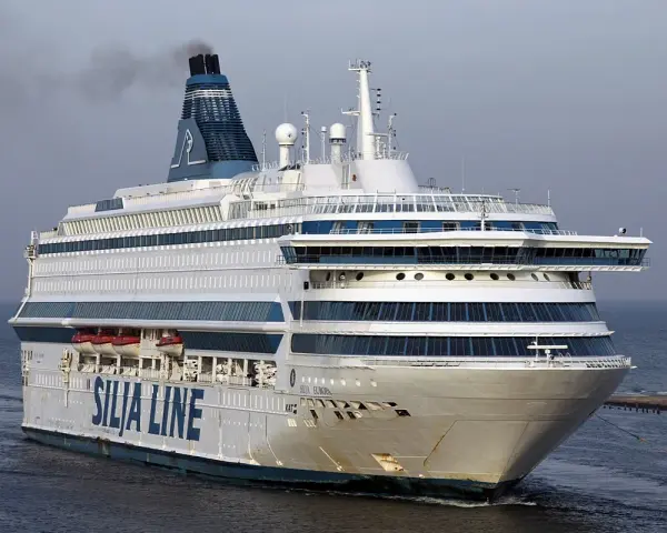 Ogromny prom pasażerski Silja Europa z charakterystycznym kominem i niebieskimi pasami na białym kadłubie płynie po spokojnym morzu.