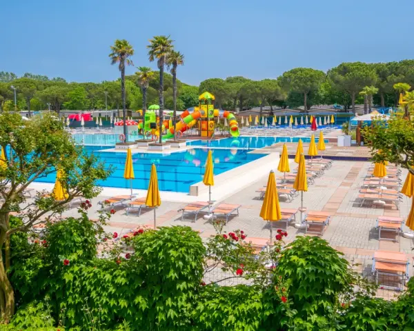 Słoneczny dzień w Portofelice Camping Village. Baseny, zjeżdżalnie i leżaki czekają na gości.