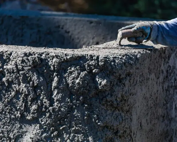 Dłoń w rękawicy wygładza mokry beton na budowie.