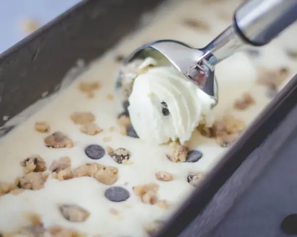 Mit einem Eisportionierer wird cremiges Cookie Dough Eis mit Schokostückchen aus einer Form gehoben. Perfekt, um Eis selber machen zu erleben!