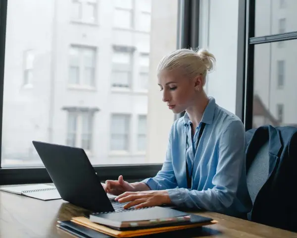 Donna bionda lavora al laptop, analizzando dati per ottimizzare lo stipendio dell'e-commerce manager.