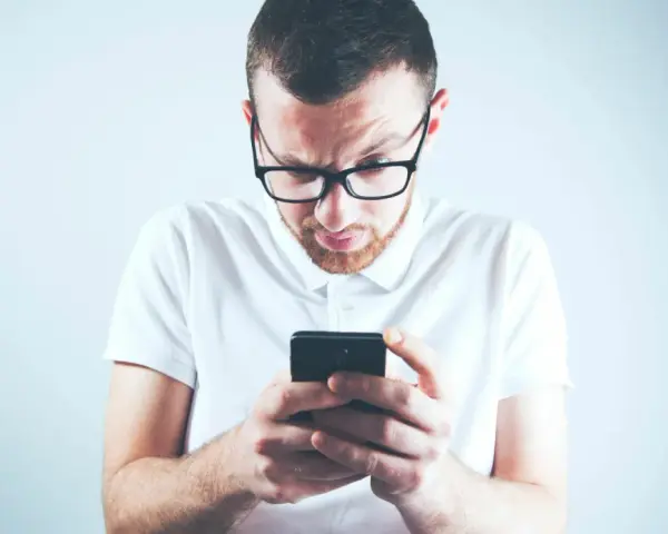 Zastanawiasz się, skąd firma windykacyjna ma Twój numer telefonu? Mężczyzna w okularach patrzy zdezorientowany na ekran smartfona.