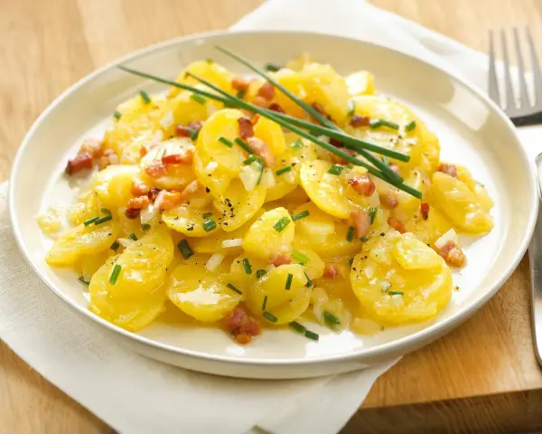 Ein Teller mit Kartoffelsalat mit Speck, garniert mit Schnittlauch. Ein Klassiker, der immer schmeckt.
