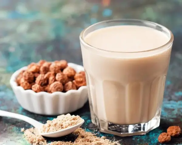 Un verre de lait de souchet crémeux, à côté d'une coupelle de tubercules et d'une cuillère de poudre.