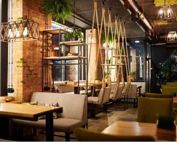 Un restaurante moderno con ladrillo visto, plantas colgantes y columpios. Un lugar acogedor que inspira lo que se necesita para abrir un restaurante.