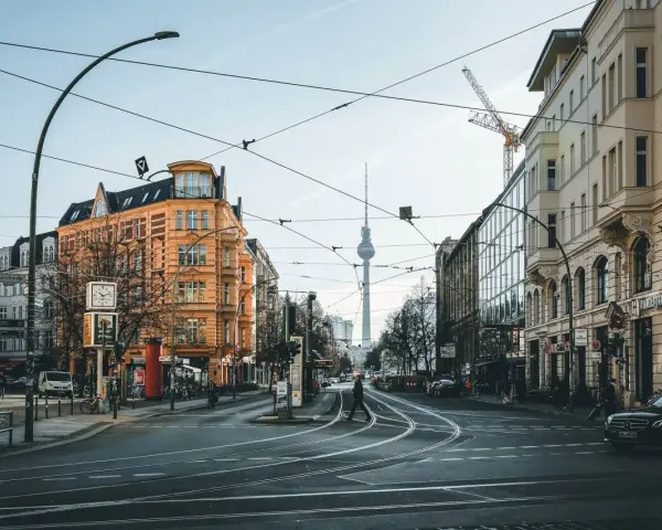 Skrzyżowanie w Berlinie z widoczną wieżą telewizyjną. Czy Berlin jest bezpieczny? Miasto tętni życiem, a ludzie swobodnie poruszają się po ulicach.