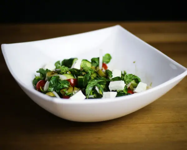Salade fraîche et colorée avec des cubes de fromage pour salade, tomates cerises, concombres et olives vertes.