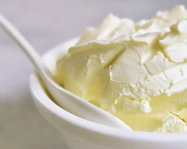 Kremowa masa w białej miseczce, idealna jako zamiennik mascarpone do deserów.