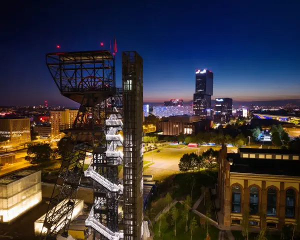 Wieżowiec kopalni węgla obok nowoczesnych budynków tworzy kontrast w nocnym megapolis.