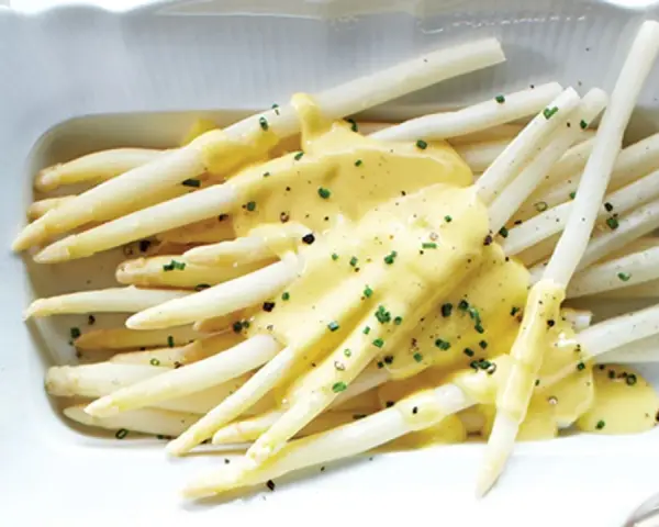 Asperges blanches nappées d'une sauce onctueuse, parsemées de ciboulette fraîche. Un délice printanier.