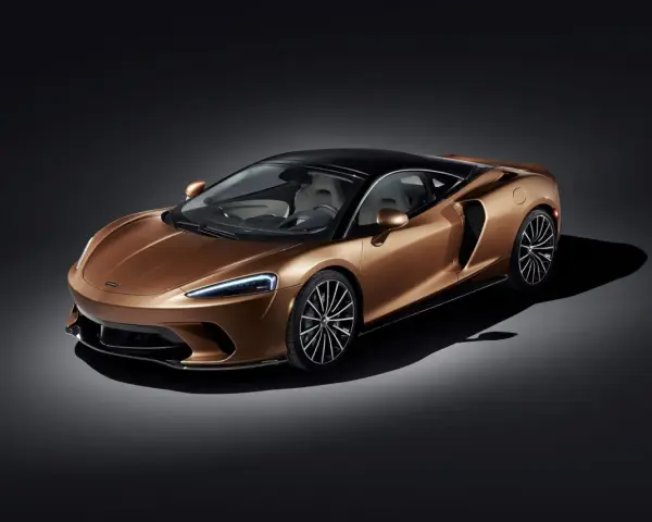 Elegancki, miedziany McLaren GT z czarnym dachem i felgami, prezentujący swoje sportowe linie na ciemnym tle.