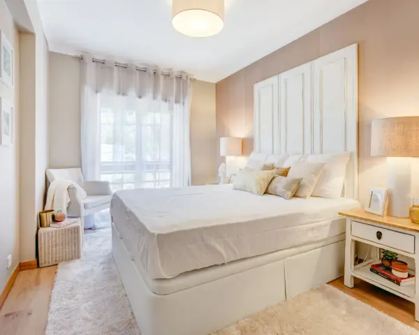 Camera da letto accogliente con letto bianco, comodino con libri e lampada. Idee su cosa mettere su como camera da letto.