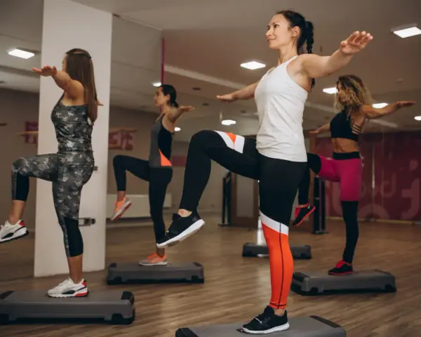 Kobiety na stepach wykonują trening aerobowy co to jest, ćwicząc równowagę i kondycję.