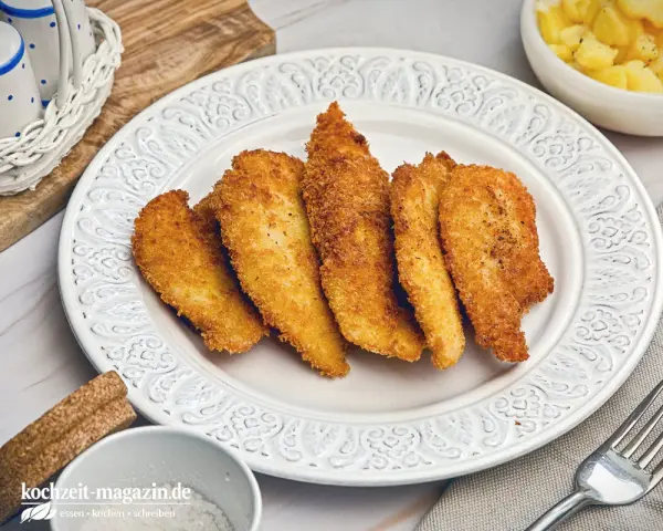 Knuspriges Wiener Backhendl, original Rezept. Goldbraun paniert und perfekt gegart, daneben Kartoffelsalat.
