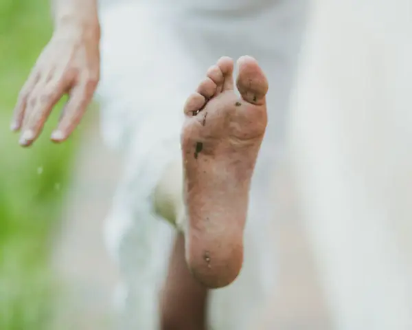 Pie sucio y descalzo, con tierra y hierba. Un consejo para como quitar el olor de los pies es lavarlos bien.