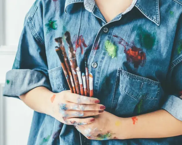 Manos manchadas de tempera y una camisa vaquera salpicada de pintura. ¡Un desafío para quitar tempera de la ropa!