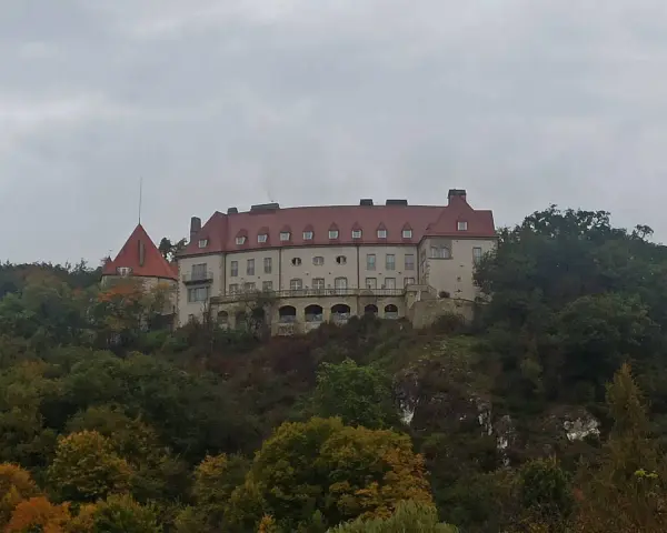 Zamek na wzgórzu, otoczony jesiennym lasem, przypomina o historii Krakowa i Kalwarii Zebrzydowskiej.