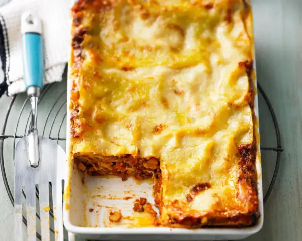Herzhaftes Lasagne Rezept mit goldbrauner Käsekruste, bereit zum Servieren. Ein Stück fehlt bereits!