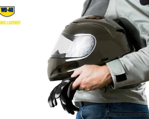 Un motociclista tiene un casco nero lucido e guanti. Scopri come pulire visiera casco per una guida sicura.