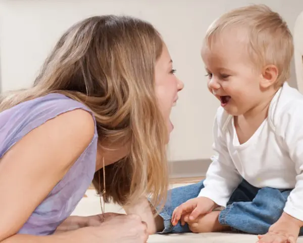 Frau und Baby lachen sich an. Sie unterhalten sich, zahlen ohne Sorgerecht, aber die Freude ist echt.