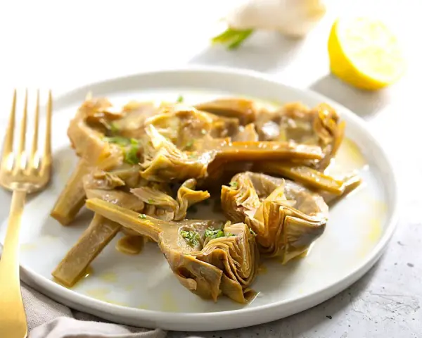 Carciofi cotti in olio e limone, pronti per essere serviti. Scopri come congelare i carciofi per averli sempre a disposizione.