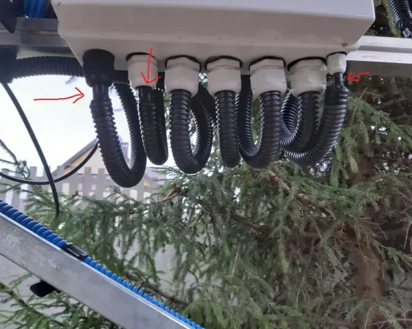 Przewody solarne w peszlu i bez, podłączone do skrzynki. Czerwone strzałki wskazują na połączenia.