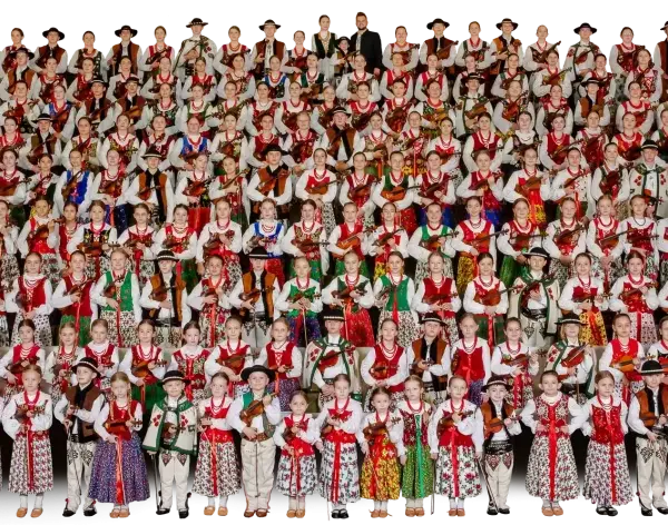 Wielka grupa dzieci i młodzieży w strojach ludowych, grających na akordeonach i skrzypcach. To piękna prezentacja muzyki ludowej Mazowsza.