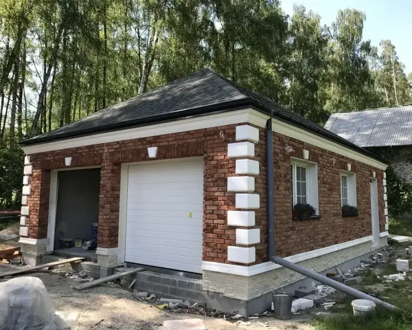 Nowy garaż z cegły z białym gzymsem i ozdobnymi elementami.