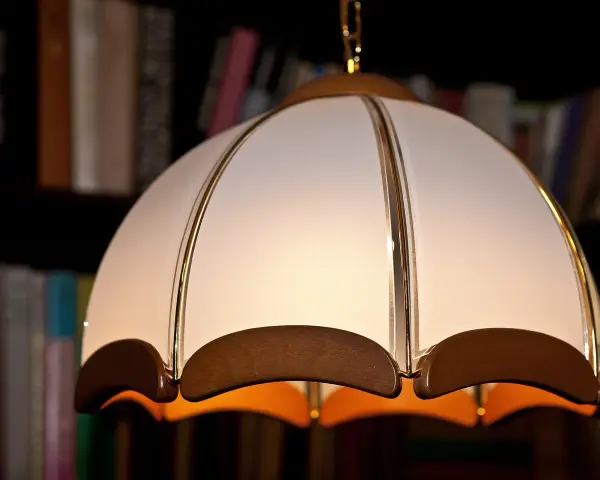 Elegancki abażur z materiału, ozdobiony złotymi paskami i drewnianymi elementami. Idealny do salonu, inspiracja jak zrobić abażur z materiału.