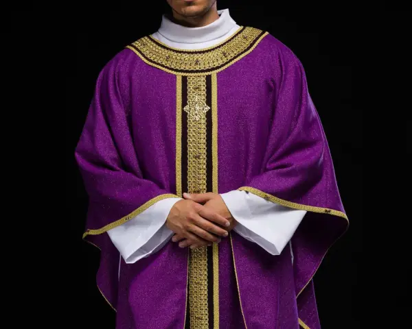 Eleganckie fioletowe szaty liturgiczne z bogatymi złotymi zdobieniami, noszone przez mężczyznę z dłońmi złożonymi na piersi.