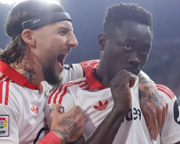 Jugadores del Sevilla FC celebran un gol contra el Atlético de Madrid. Uno grita con euforia, el otro reflexiona.