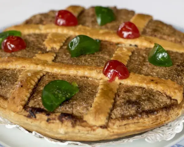 Tarta de Mondoñedo, un dulce tradicional con masa dorada, relleno de frutos secos y decorada con cerezas rojas y verdes.
