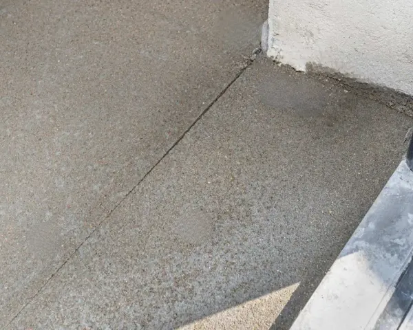 Dylatacja betonu na zewnątrz, widoczna linia podziału na świeżo wylanej nawierzchni, zapobiegająca pękaniu.
