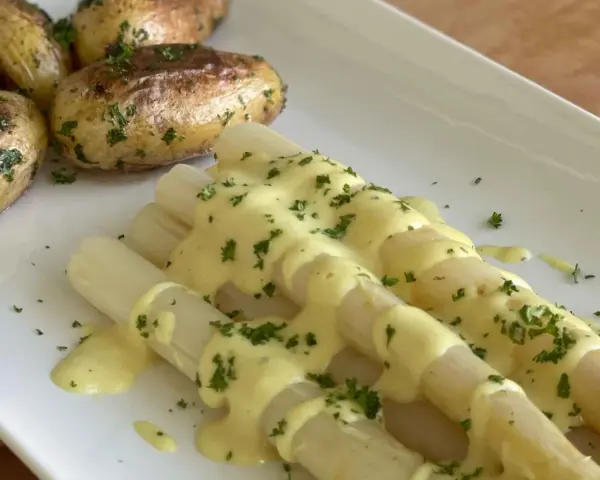 Weißer Spargel mit Kartoffeln und cremiger, veganer Hollandaise, bestreut mit frischer Petersilie. Ein Genuss!