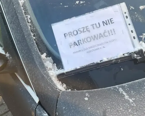 Na przedniej szybie samochodu, pokrytej szronem, widnieje kartka z napisem "Proszę tu nie parkować!!! Parking tylko dla mieszkańców bloku".