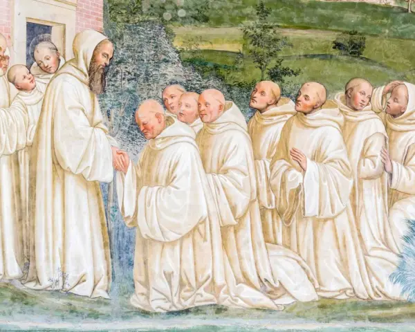 A bearded monk greets a line of novices, their white robes hinting at a rich monk history.