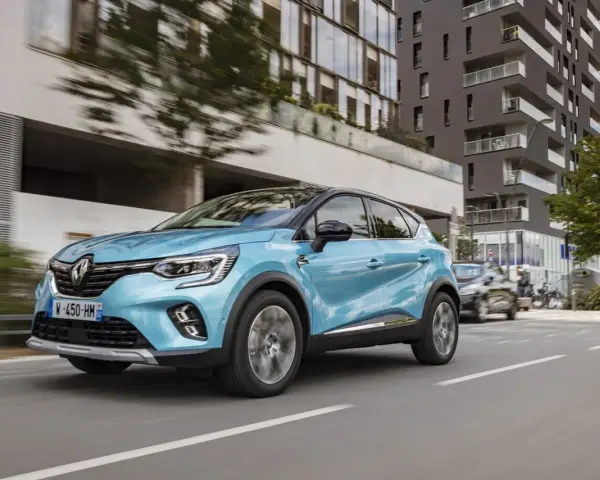 Un Renault Captur azul circula por una ciudad moderna. Es un híbrido no enchufable, eficiente y elegante.