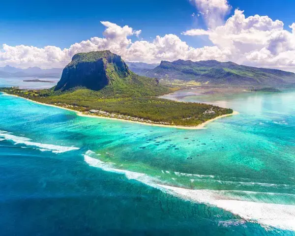 Mauritius pogoda październik: turkusowa woda, zielona góra Le Morne Brabant i białe chmury. Idealna pogoda na rajskie wakacje.
