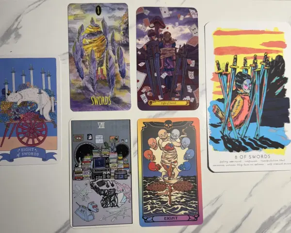 Cinco cartas del tarot, la mayoría con espadas, sobre un fondo blanco.
