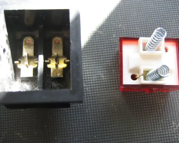 Detalle del interruptor de paso por dentro: contactos metálicos en un lado y resortes en el otro, listos para conectar.