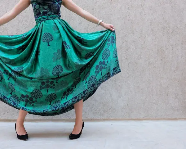 Abito color ottanio con fantasia di alberi. Scarpe nere eleganti completano il look.