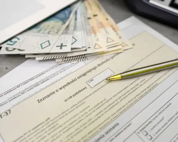 Pieniądze i formularz PIT-37. Zastanawiasz się, jaka jest kwota wolna od podatku? Długopis czeka na wypełnienie zeznania.